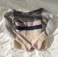 a crocheted sweater laying on top of a bed