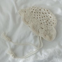 a crocheted hat with tassels on a white bed