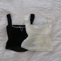 two black and white crocheted tops on a bed