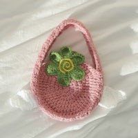 a pink crocheted bag with a flower on it