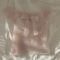 a pink knitted top with a bow on it