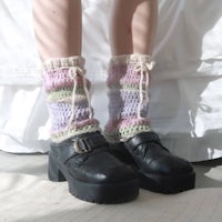 a woman wearing a pair of black boots and crocheted socks